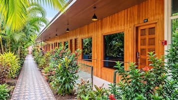 Un bâtiment en bois doté d’une allée couverte, de plantes en pot et surplombé d’un ciel dégagé.
