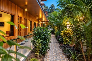 A corridor with wooden walls, potted plants, and a tiled pathway. - Hotel Golden Pebble (Port Blair)