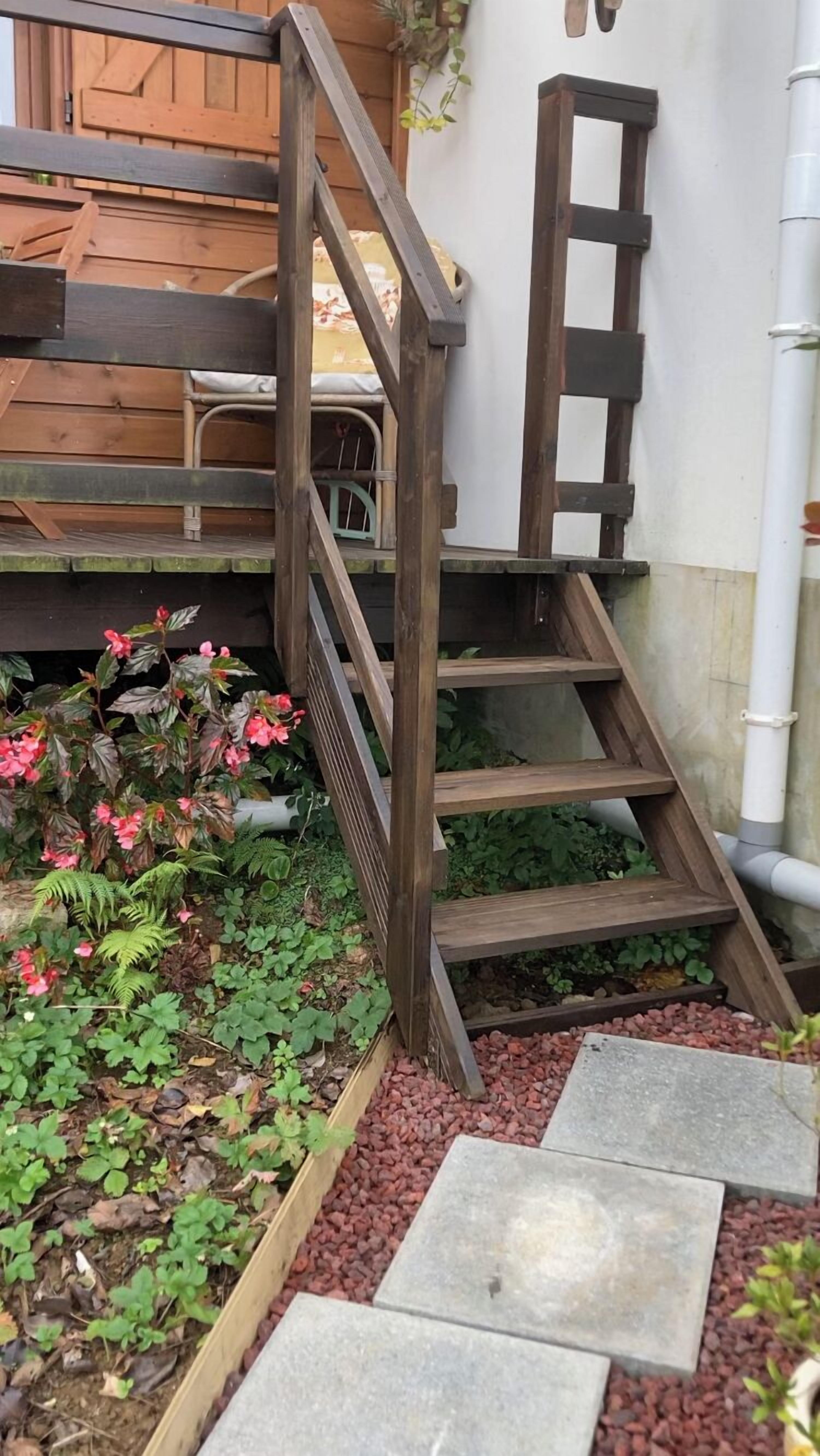 A wooden staircase leading up to a wooden deck with a bench.