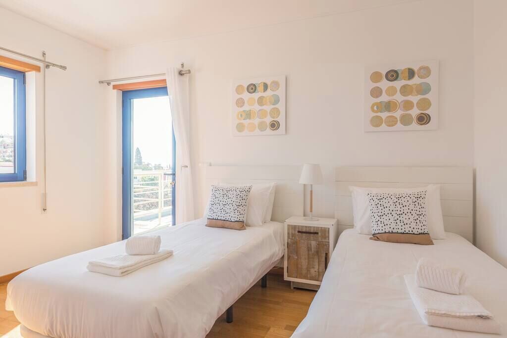 A hotel room with two beds, a window with curtains, and wall art.