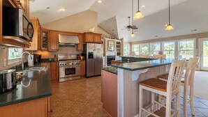 A spacious kitchen with a large island, modern appliances, and a view of the outdoors. - Show Boat - Kitty Hawk MP 2.5, Pool, Hot Tub, Rec Room, Pool Table, Golf Course Views (Kitty Hawk)