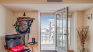 A room with a leather chair, a small table, a decorative net, and a view of the outside.