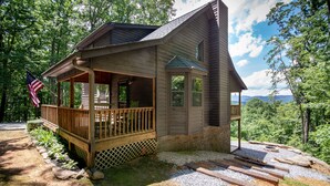 Une cabane dotĂ©e dâun porche, dâune terrasse et offrant une vue sur la forĂȘt environnante.