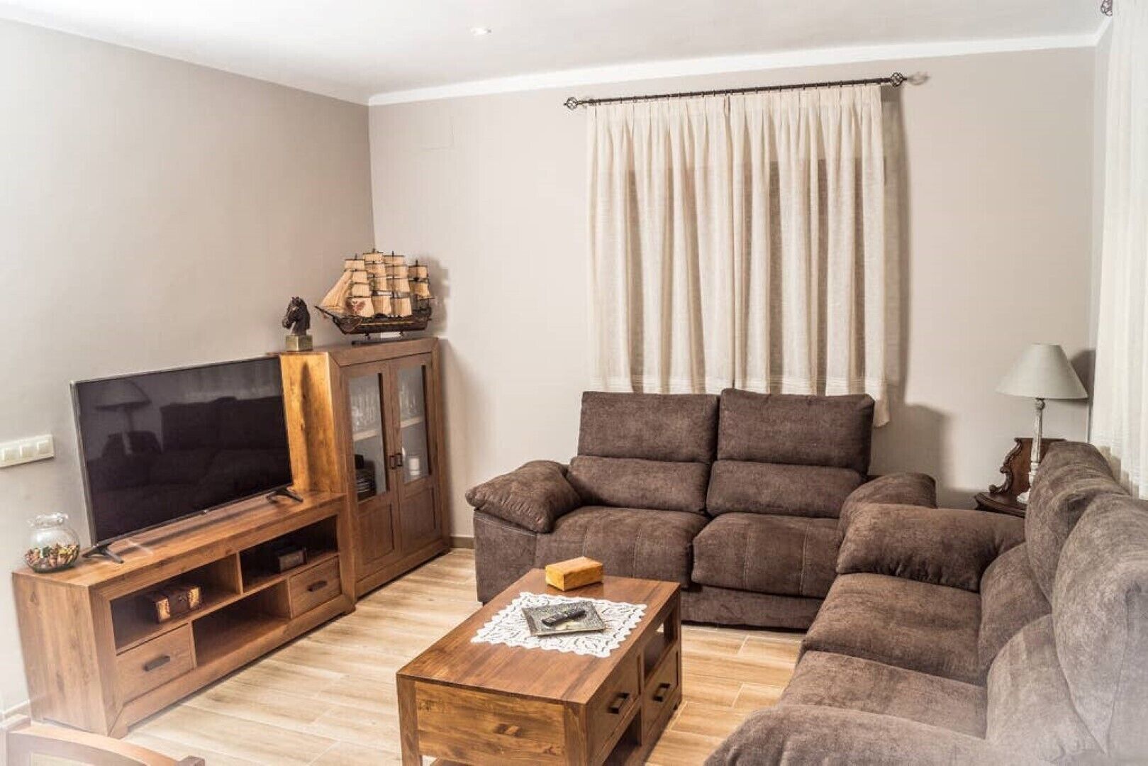 A living room with a television, wooden cabinet, and a sofa.