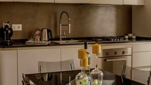 Eine kleine Küche mit Gaskochfeld, Kaffeemaschine und Wasserkocher auf der Arbeitsplatte. Über der Arbeitsplatte befinden sich Schränke und darunter der Herd.