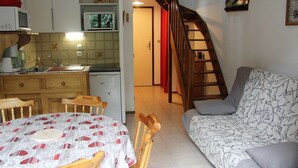 A compact living space with a kitchen area, dining table, and a sofa. - Quiet 3-Room Duplex with Covered Parking, Balcony, Near Ski Slopes (La Clusaz)