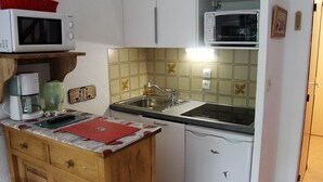 A compact kitchen with white cabinets, a sink, a microwave, a coffee maker, and a refrigerator. - Quiet 3-Room Duplex with Covered Parking, Balcony, Near Ski Slopes (La Clusaz)