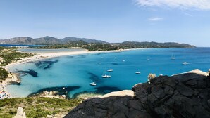 Paisaje costero con aguas azul turquesa, embarcaciones y una playa.
