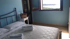 Un dormitorio con cama, ventana con vistas, mesita de noche y cesta.