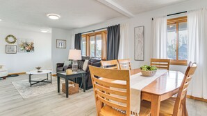 Un soggiorno moderno con zona pranzo, che include un tavolo da pranzo in legno, sedie, un divano e un tavolino.