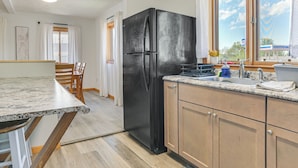 Una cucina moderna con frigorifero nero, mobili in legno e piano di lavoro in granito.