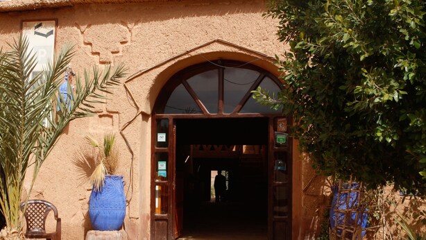 A rustic entrance with a wooden archway, a large blue vase, and a chair outside. - Guest House The Dor fibula (Aït Ben Haddou)