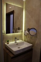 Un baño con un lavamanos blanco, un espejo y un secador de pelo.