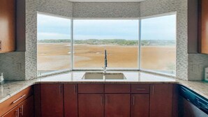 A kitchen with a large window, a sink, and cabinets.