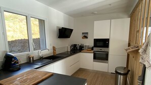 A modern kitchen with white cabinets, a black countertop, a microwave, an oven, and a sink.