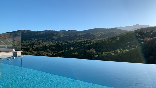 An infinity pool with a clear view of a mountainous landscape.