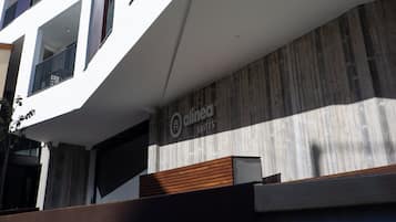 A modern building with a white facade, multiple balconies, and a sign for 'dinea Suites'.