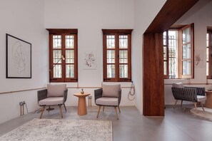 Una sala de estar moderna con dos sillones, una mesita redonda y obras de arte en las paredes.