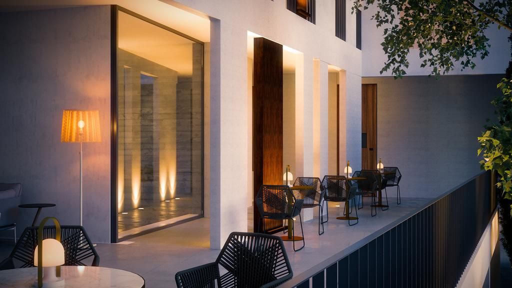 Un espacio al aire libre moderno con mesas y sillas, un muro de vidrio y una puerta de madera.