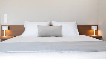 Un letto ben rifatto con lenzuola bianche e una coperta a quadri, affiancato da due comodini con lampade.