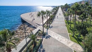 A coastal promenade with a paved walkway, palm trees, and a view of the sea. - Alinea Suites Limassol Center (Limassol)