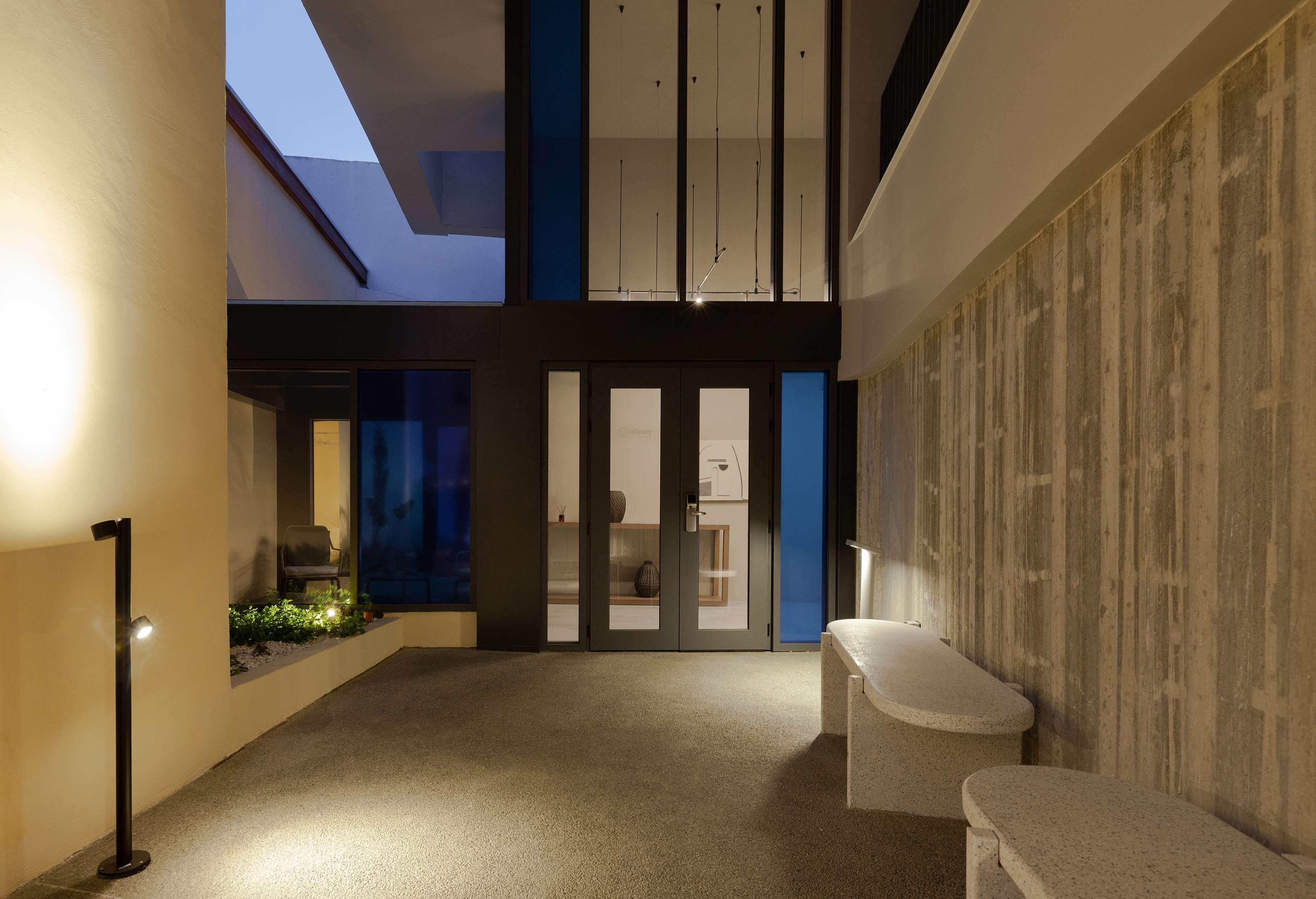 A modern interior with a high ceiling, a seating area, and a view through a glass door.