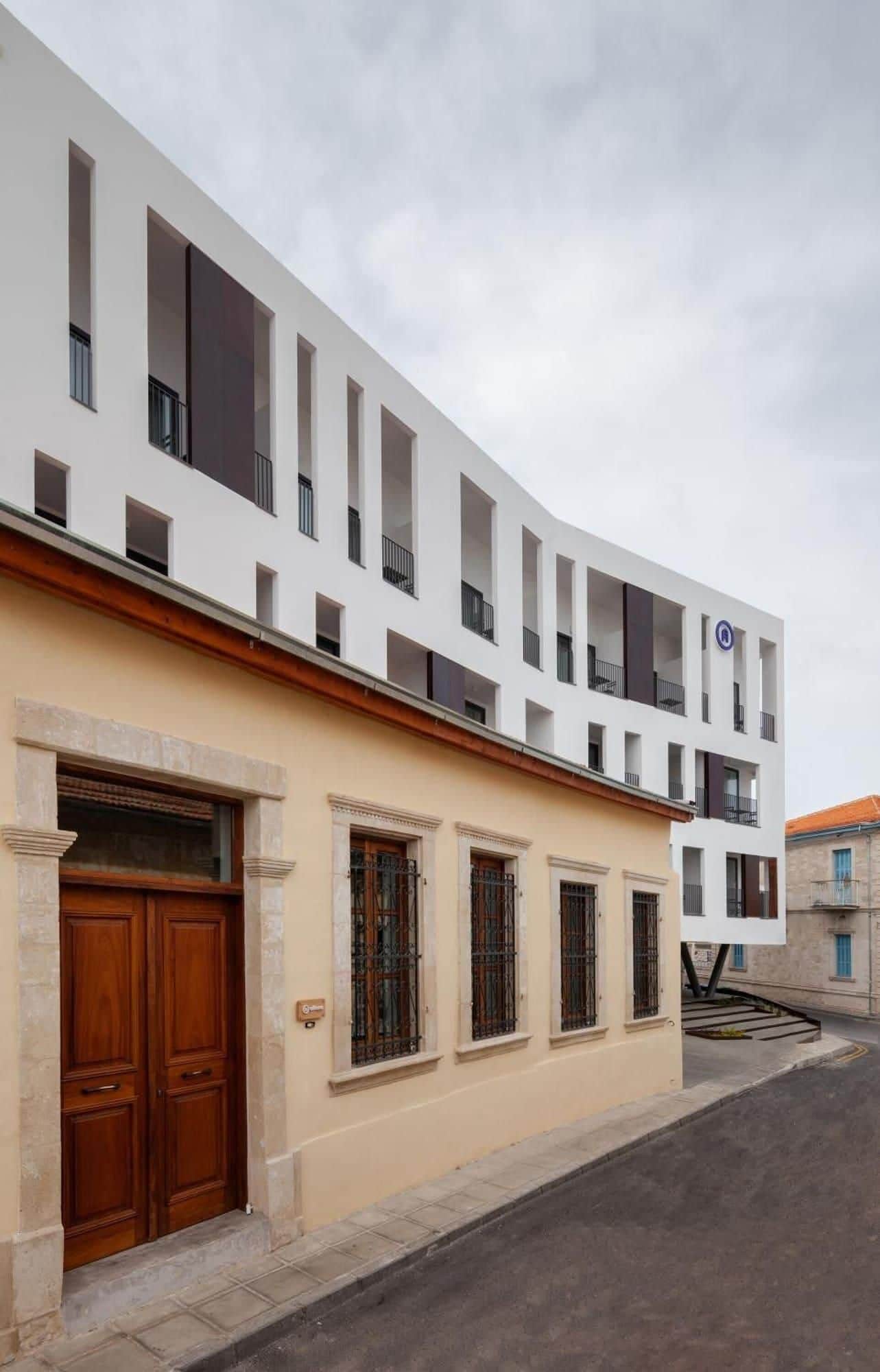 Un edificio moderno con fachada plana, ventanas grandes y entrada a nivel de calle con puertas de madera dobles.