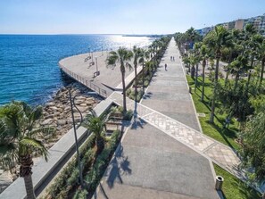 A coastal promenade with a paved walkway, palm trees, and a view of the sea. - Alinea Suites Limassol Center (Limassol)