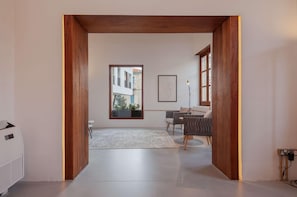 Un interno moderno con una porta in legno, un'area pranzo con tavolo e sedie, e un'ampia finestra che offre vista all'esterno.