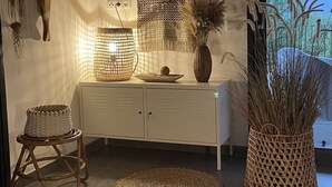 Un intérieur moderne avec un meuble blanc, des paniers tressés, un tapis tissé et des éléments décoratifs suspendus au mur.