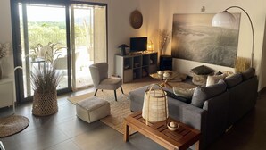 Un salon moderne avec un canapé gris, une table basse en bois et un grand tableau accroché au mur.