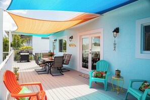 Eine überdachte Terrasse im Freien mit Grill, Sitzgelegenheit und einer Schiebeglasdoor.