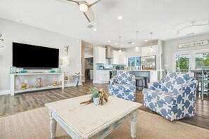 A modern living room with a flat-screen TV, a coffee table with a plant, and star-patterned armchairs.