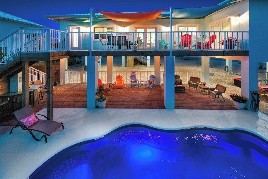 A two-story house with a swimming pool, outdoor seating, and a covered patio.