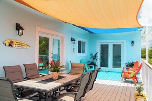 An outdoor patio with a table and chairs, a covered area, and potted plants.