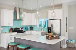 A modern kitchen with white cabinets, a central island, and pendant lighting.