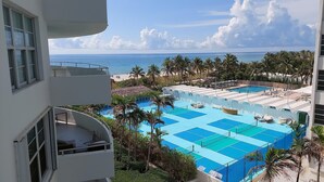 A resort with a large pool area, palm trees, and a view of the ocean.