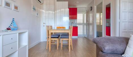 A modern apartment with a dining area, a sofa, and a kitchenette.