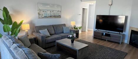 Ett modernt vardagsrum med en grå soffgrupp, ett soffbord och en platt-TV.