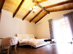 A bedroom with a wooden ceiling, a bed, a bench, and a window with curtains. - Hotel Bylis (Tirana)