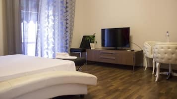 Une chambre d’hôtel avec un lit, une télévision, un bureau avec une plante et une chaise.