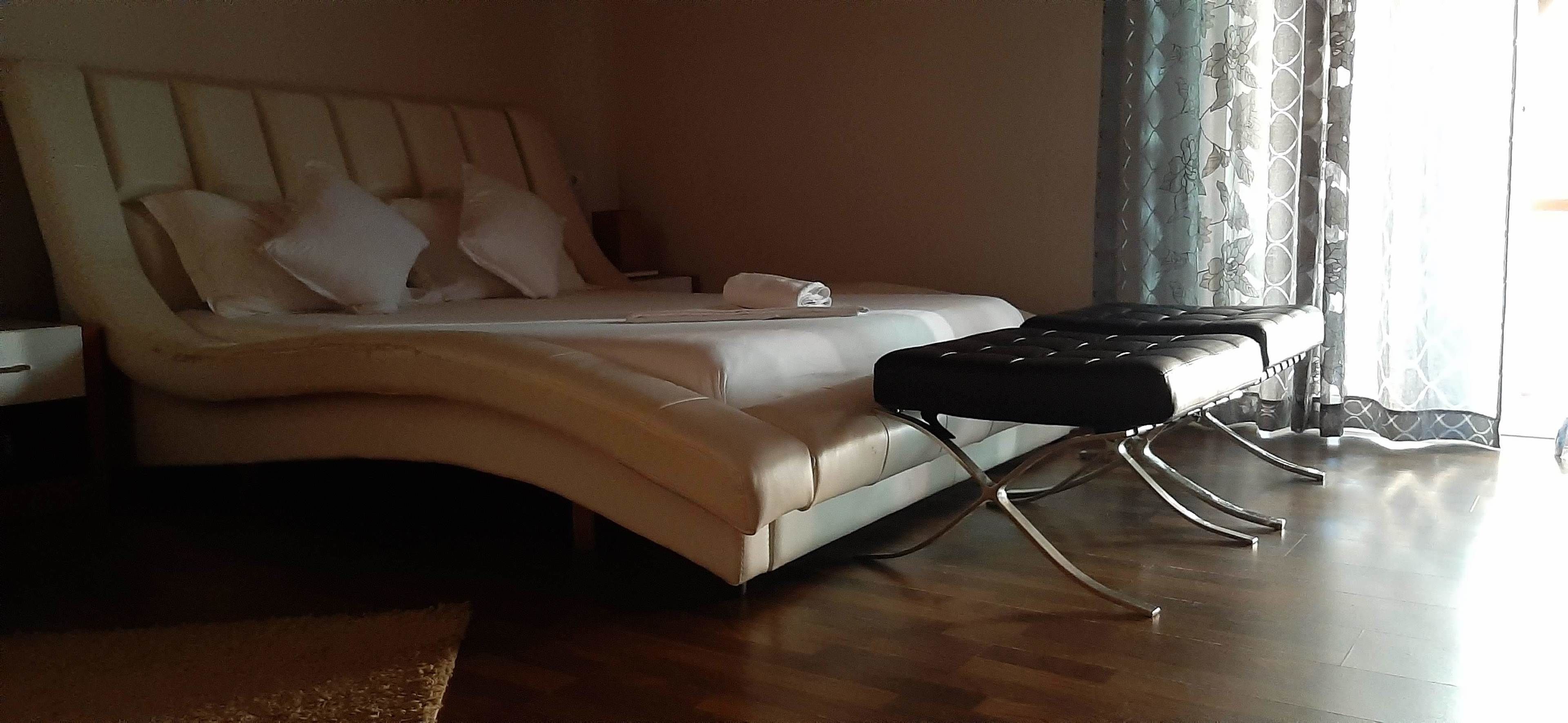 Un dormitorio con cama, almohadas, una mesita de noche y una silla.