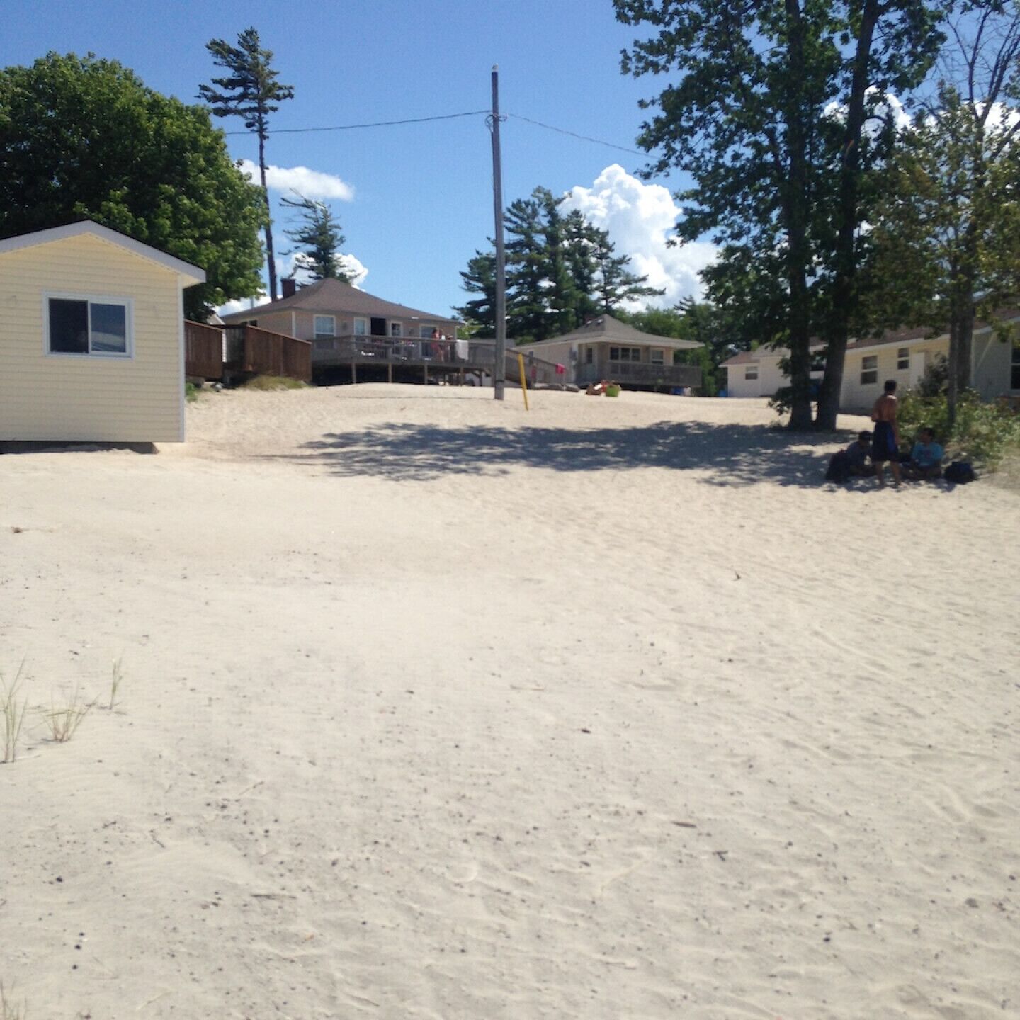 A residential area with houses, a small shed, and a sandy ground.
