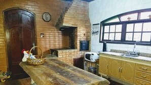 A rustic kitchen with a wooden table, a brick oven, and wooden cabinets. - HOUSE IN PENEDO WITH WATERFALL (Penedo)