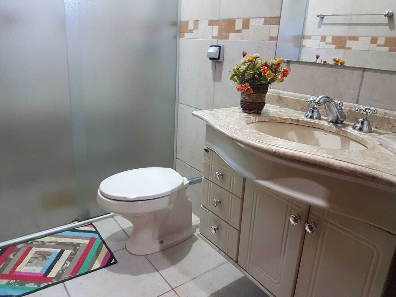 A bathroom with a toilet, a sink, and a cabinet.