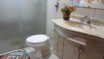 A bathroom with a toilet, a sink, and a cabinet.