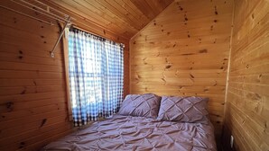 A single bed with a quilted cover in a cabin with wooden walls and a sloped ceiling. - BEACHFRONT COTTAGE IN WASAGA BEACH - SANDPIPER BEACH RESORT - COTTAGE # 9 (Wasaga Beach)