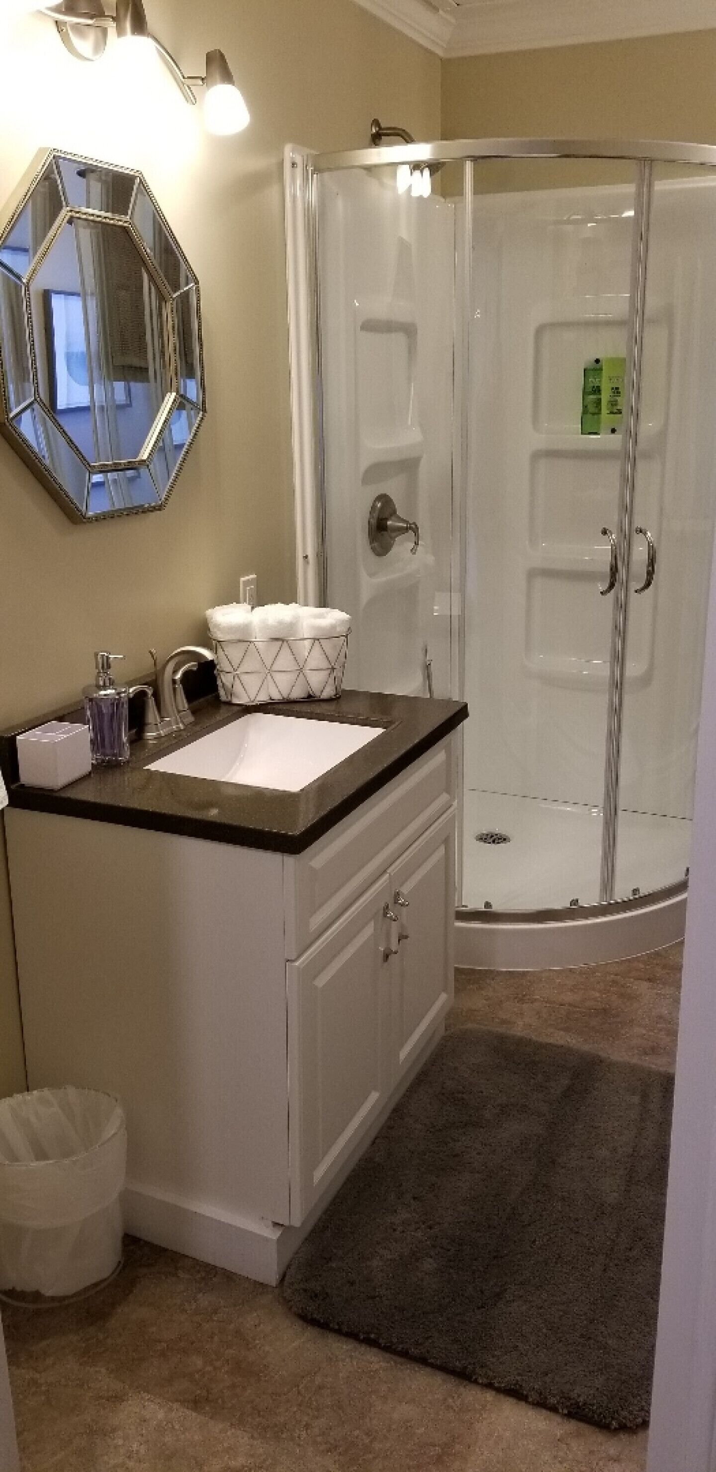 Un baño con lavamanos blanco, espejo, ducha y toallero.