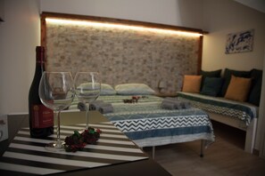 A room with a bed, a table with a bottle and glasses, and a patterned bedspread. - Civico 24 one-room apartment Monte Rosa (Scicli)