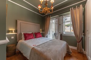 A neatly made bed with a beige headboard, red pillows, and a white bedspread.